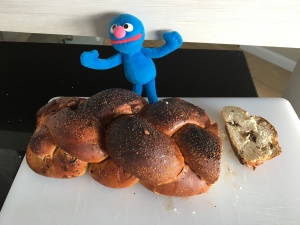 Stuffed Grover standing by raisin challah that's been cut